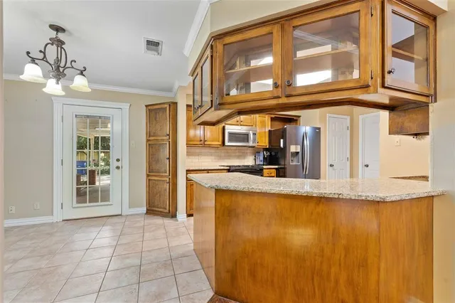 a view of a kitchen with stainless steel appliances granite countertop a refrigerator and a stove top oven