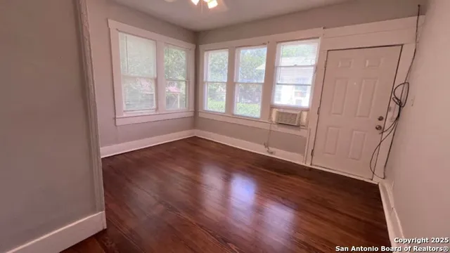 an empty room with wooden floor and windows