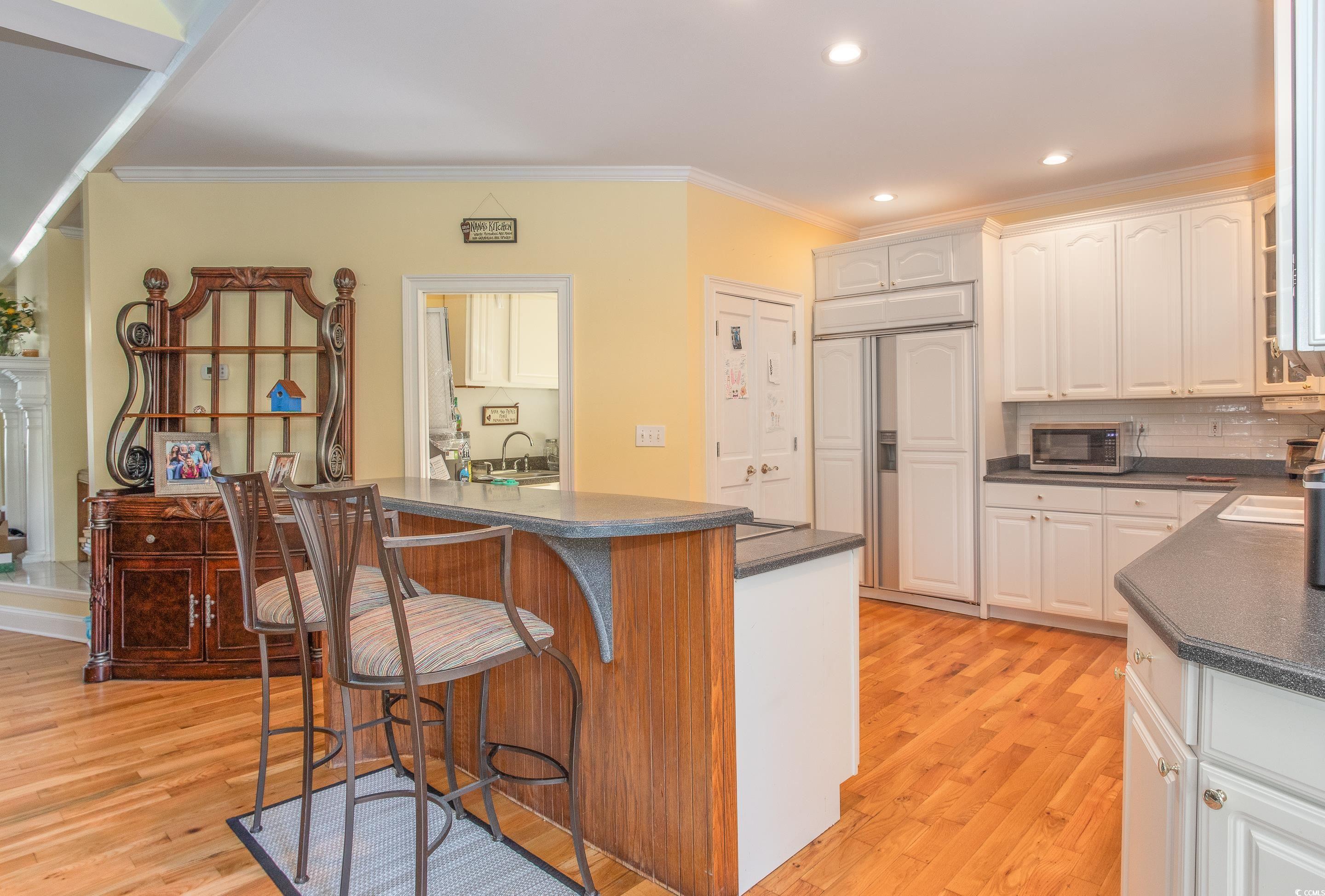 4907 Woodview Lane Myrtle Beach, SC 29575 - Photo 3 of 30 Kitchen featuring dark countertops, light wood-style floors, a kitchen breakfast bar, paneled fridge, and recessed lighting