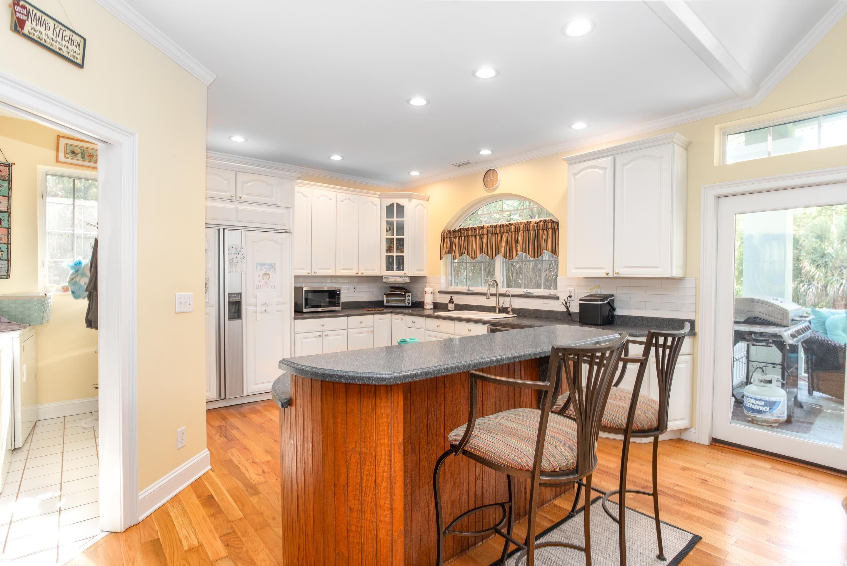4907 Woodview Lane Myrtle Beach, SC 29575 - Photo 4 of 30 Kitchen with dark countertops, tasteful backsplash, paneled built in fridge, a kitchen bar, and white cabinetry
