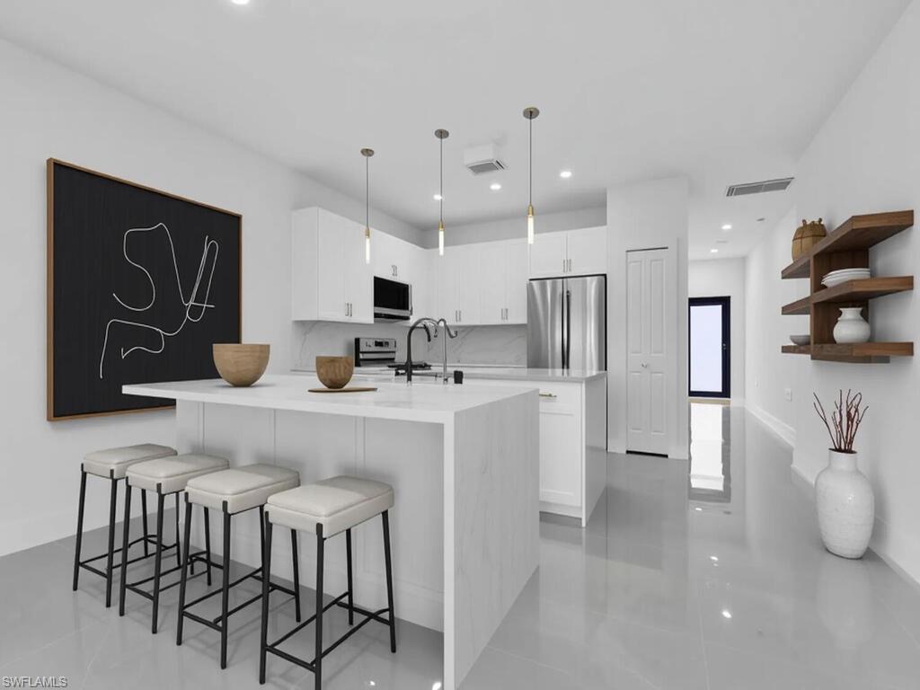 2212-2214 Wilson Road Lehigh Acres, FL 33973 - Photo 29 of 49 a kitchen with stainless steel appliances kitchen island granite countertop a refrigerator and microwave