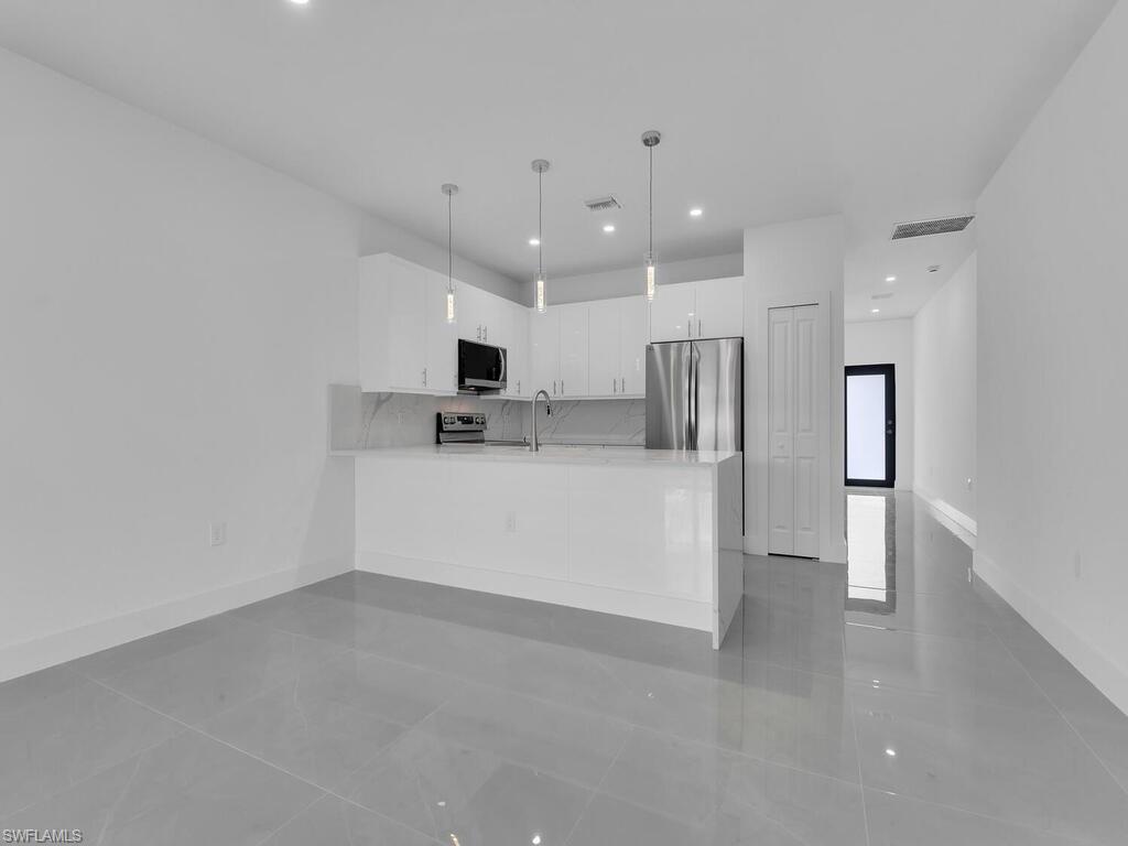 2212-2214 Wilson Road Lehigh Acres, FL 33973 - Photo 30 of 49 a view of kitchen with stainless steel appliances refrigerator a microwave and white cabinets