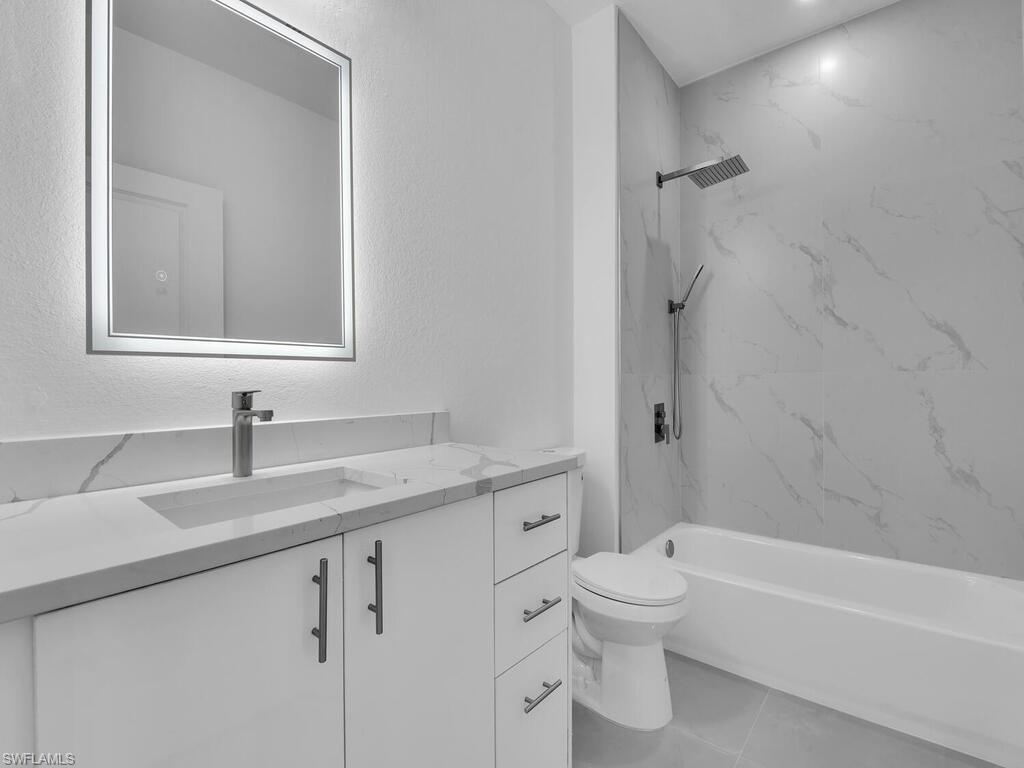 2212-2214 Wilson Road Lehigh Acres, FL 33973 - Photo 45 of 49 a bathroom with a granite countertop toilet a sink and a bathtub