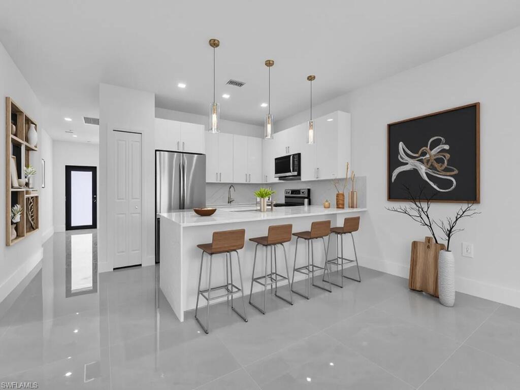 2212-2214 Wilson Road Lehigh Acres, FL 33973 - Photo 5 of 49 a kitchen with white cabinets and stainless steel appliances