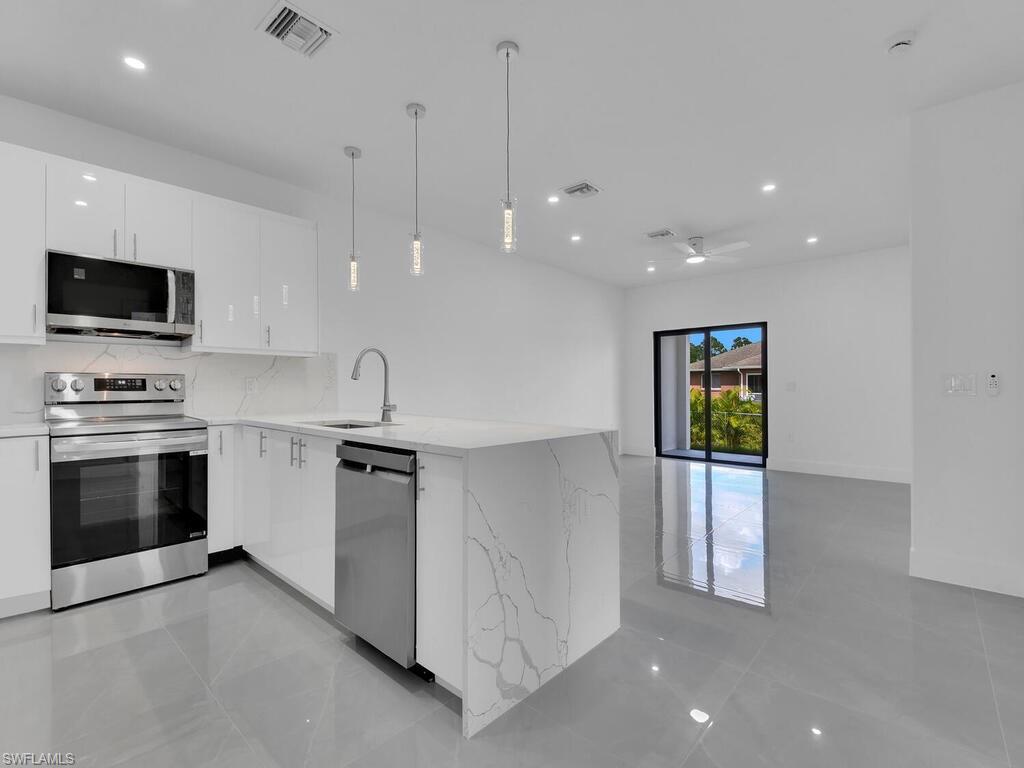 2212-2214 Wilson Road Lehigh Acres, FL 33973 - Photo 7 of 49 a kitchen with stainless steel appliances kitchen island granite countertop a stove a sink and a microwave