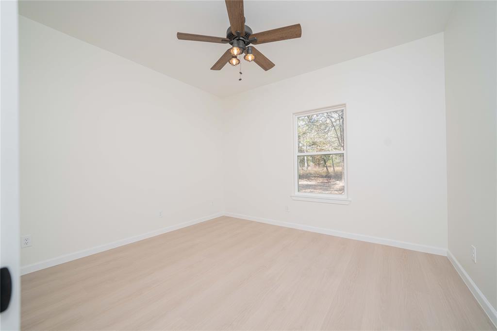 711 King Charles Road Scroggins, TX 75480 - Photo 11 of 39 an empty room with a window and a fan