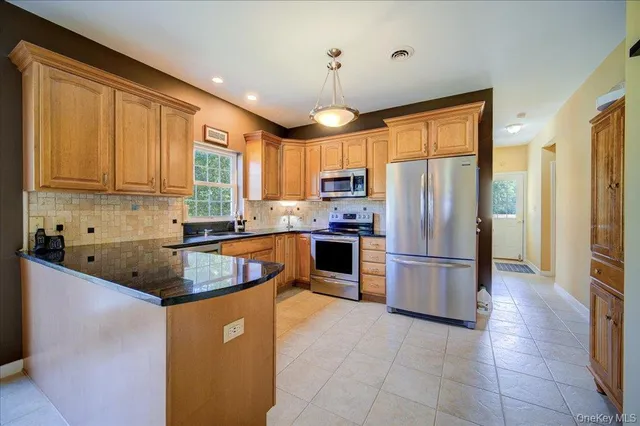 a kitchen with stainless steel appliances granite countertop a refrigerator a sink a stove top oven and a refrigerator