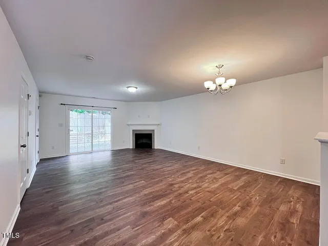 an empty room with wooden floor chandelier and windows