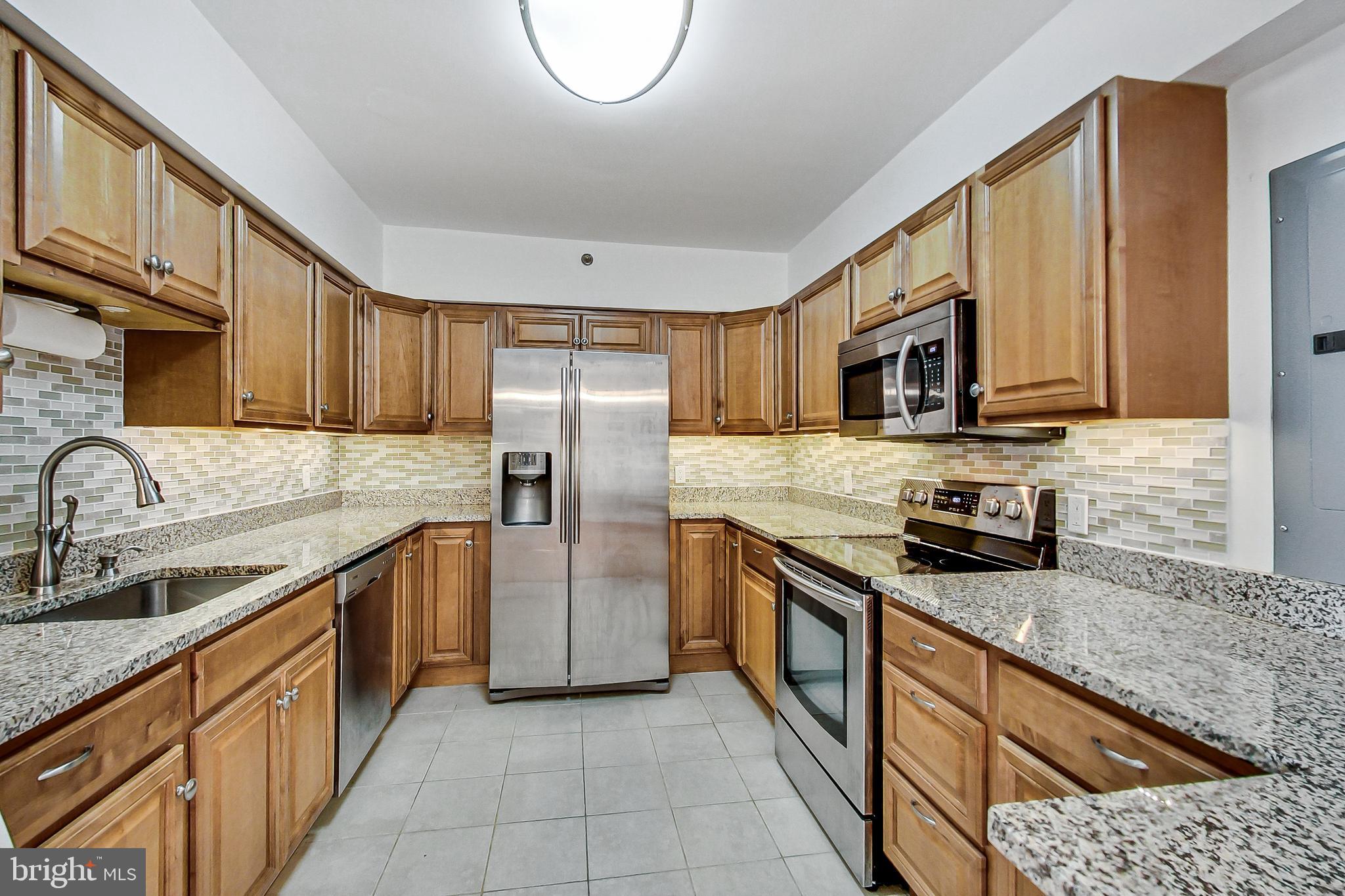 a kitchen with stainless steel appliances granite countertop a sink stove microwave and refrigerator