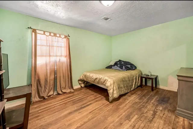 a bedroom with a bed and a flat tv screen on a dresser