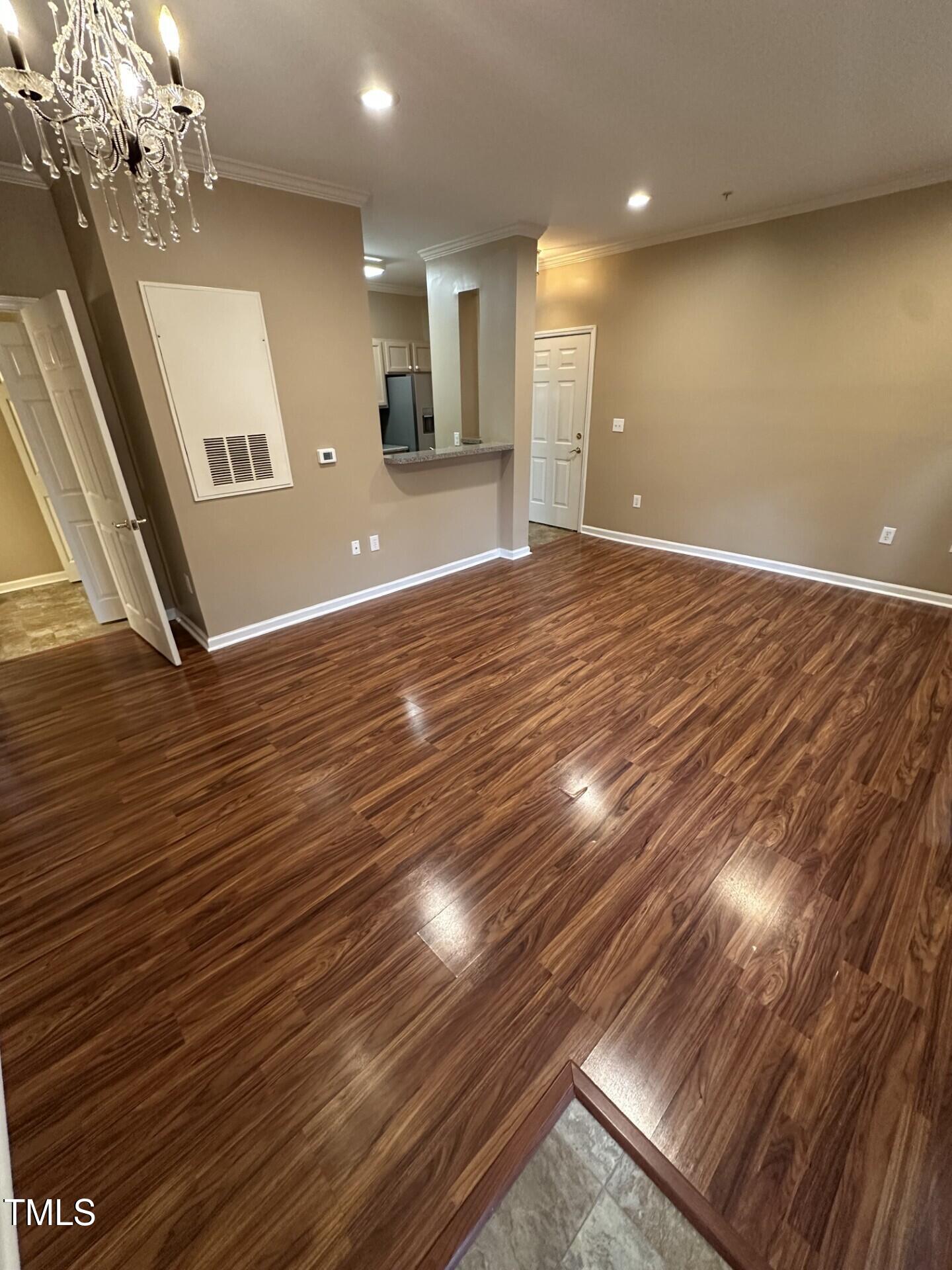 710 North Person Street, Unit 103 Raleigh, NC 27604 - Photo 6 of 16 a view of an empty room with wooden floor and a kitchen