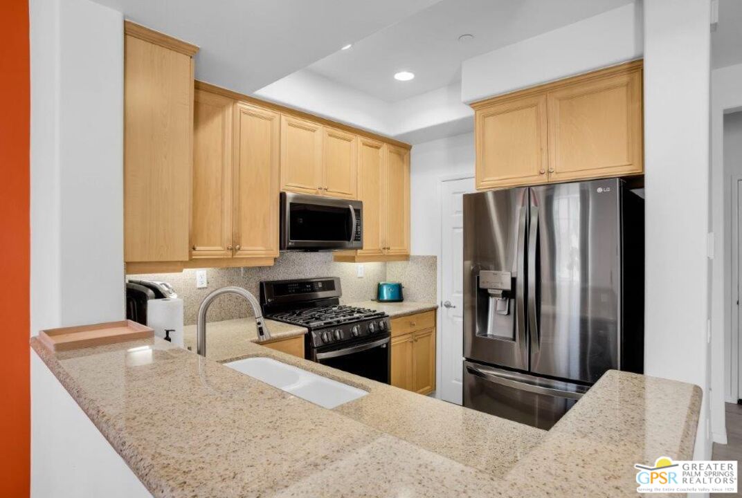435 Copper Canyon Road, Unit 23 Palm Springs, CA 92262 - Photo 9 of 28 a kitchen with a refrigerator a stove and a sink with wooden floor