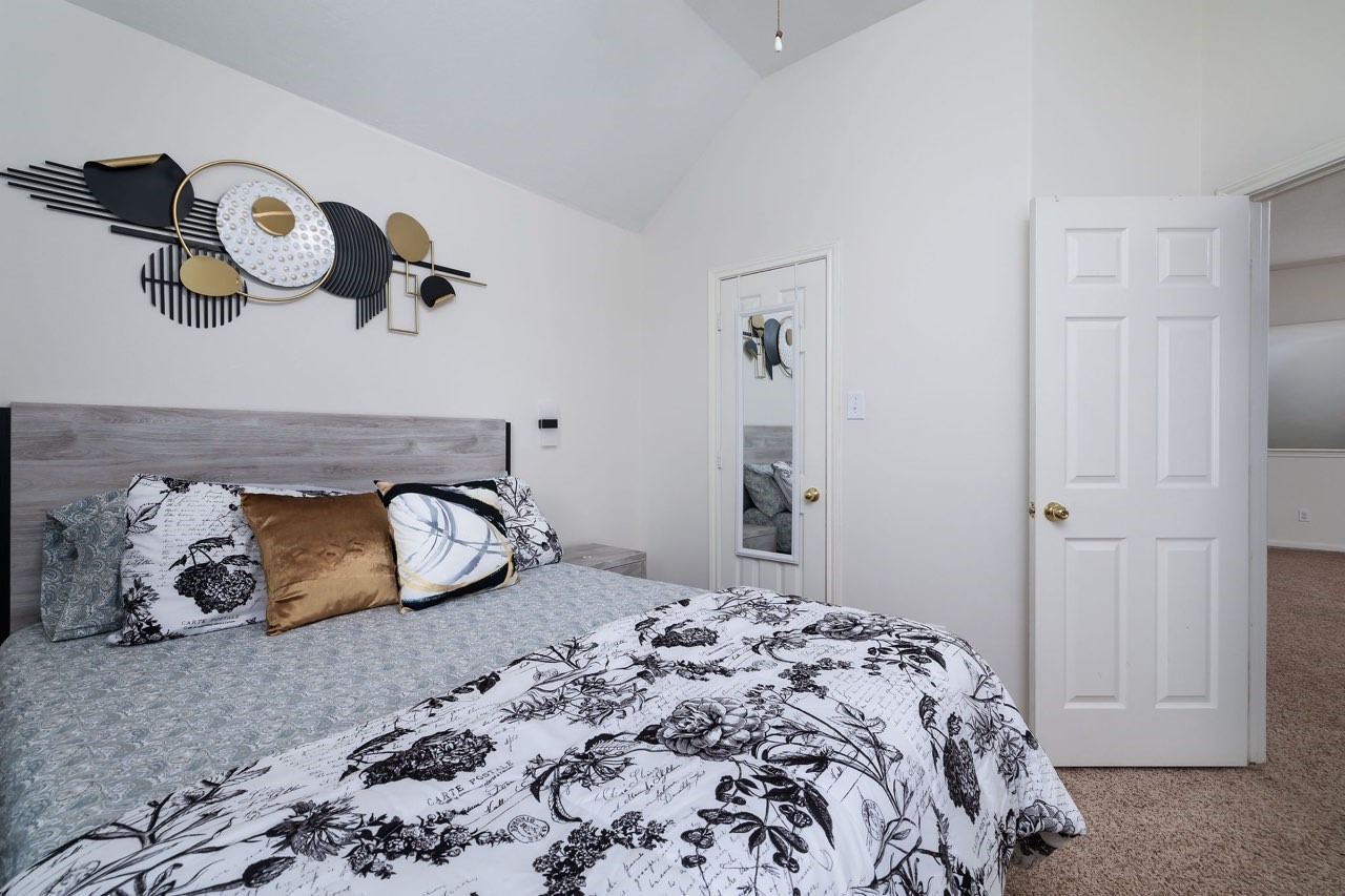 19 East Popular Pine Northeast Conroe, TX 77302 - Photo 11 of 20 a bedroom with a bed and a chandelier