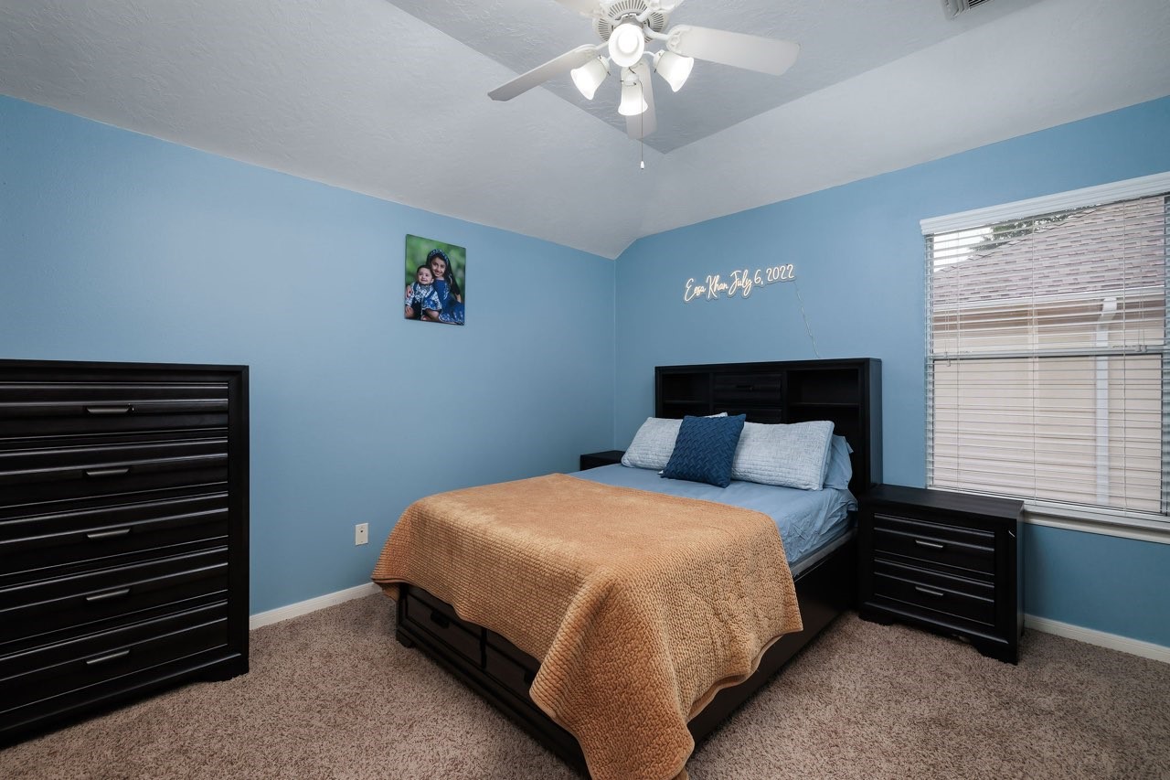 19 East Popular Pine Northeast Conroe, TX 77302 - Photo 15 of 20 a bedroom with a bed and a chandelier