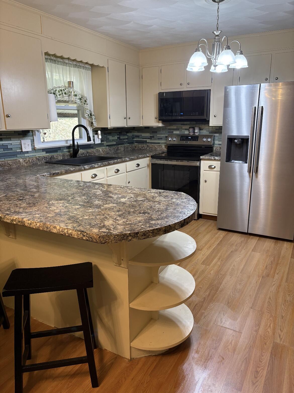 7592 Willow Branch Road Boones Mill, VA 24065 - Photo 6 of 47 a kitchen with stainless steel appliances granite countertop a sink a stove a microwave a refrigerator cabinets and wooden floor