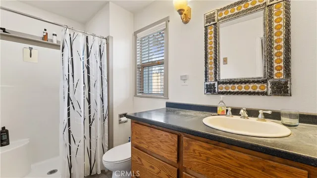 a bathroom with a granite countertop sink toilet a mirror and shower