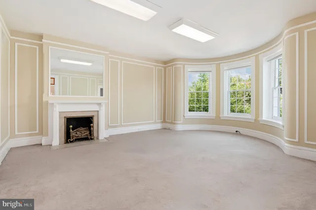 a view of an empty room with a window and fireplace