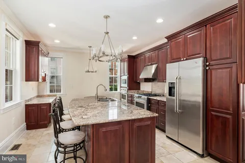 a kitchen with granite countertop kitchen island stainless steel appliances a refrigerator a sink cabinets and a dining table