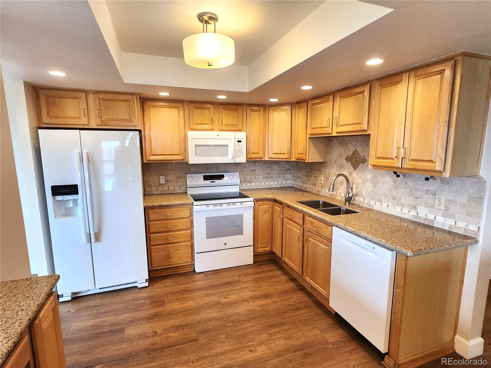 13890 East Marina Drive, Unit 602 Aurora, CO 80014 - Photo 12 of 27 a kitchen with stainless steel appliances granite countertop a refrigerator a sink dishwasher a stove and white cabinets with wooden floor