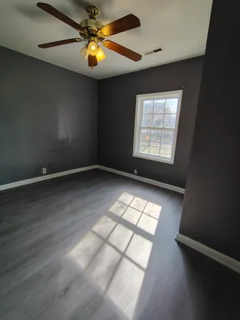 an empty room with windows and fan