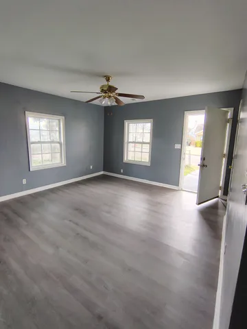 a view of an empty room with a window and wooden floor