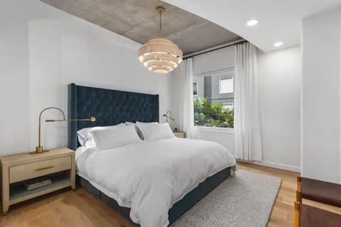 a view of an empty room with wooden floor and fan