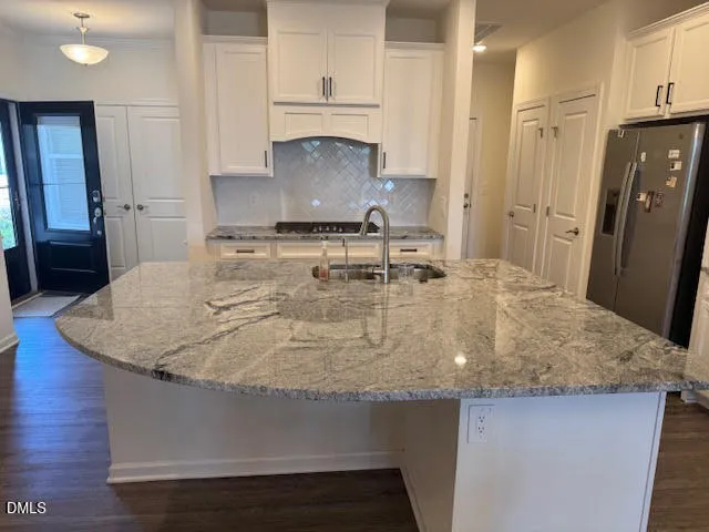 a kitchen with kitchen island granite countertop a sink a stove and refrigerator