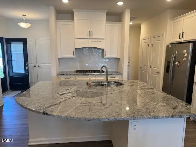 a kitchen with kitchen island granite countertop a sink a refrigerator and a stove