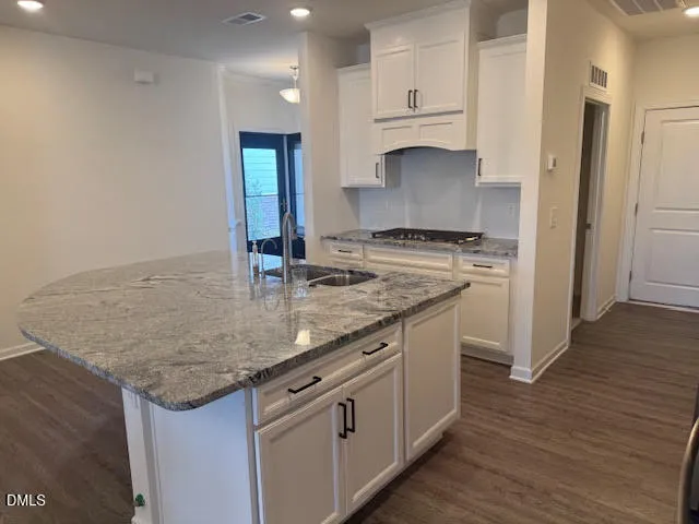 a kitchen with granite countertop a sink stove and cabinets