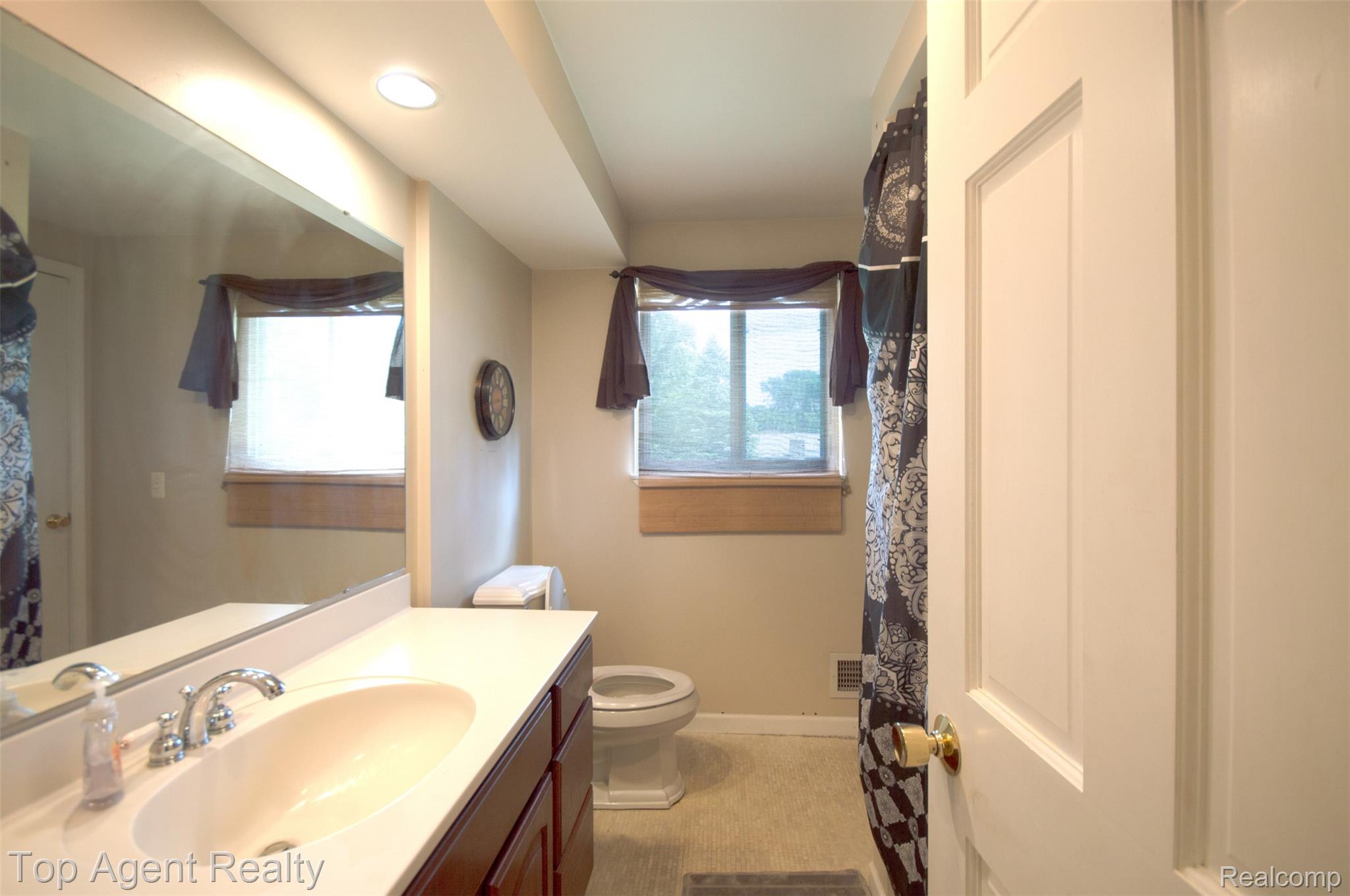 36218 Paddock Drive Clinton Township, MI 48035 - Photo 22 of 22 Bathroom vanity featuring an integrated sink with a chrome faucet, under-counter cabinetry, and a large wall-mounted mirror