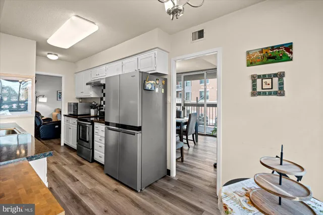 a kitchen with a refrigerator a stove and a dining table with wooden floor