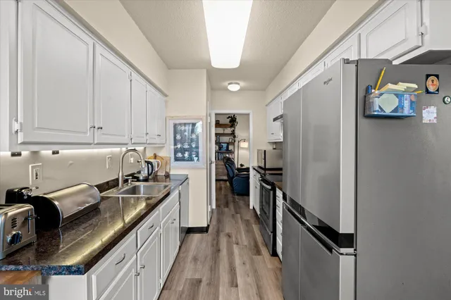 a kitchen with stainless steel appliances granite countertop a refrigerator a stove and a sink with wooden floor