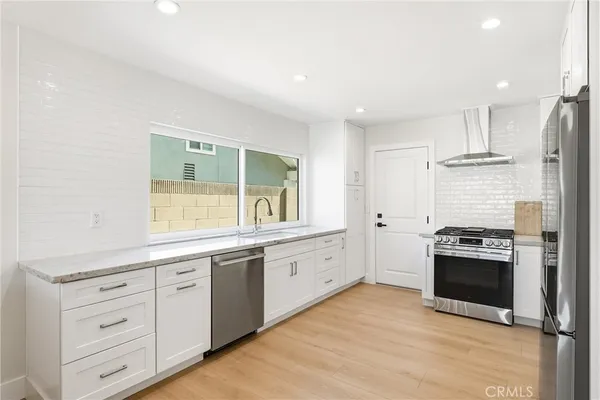 a kitchen with stainless steel appliances granite countertop a refrigerator and a stove top oven
