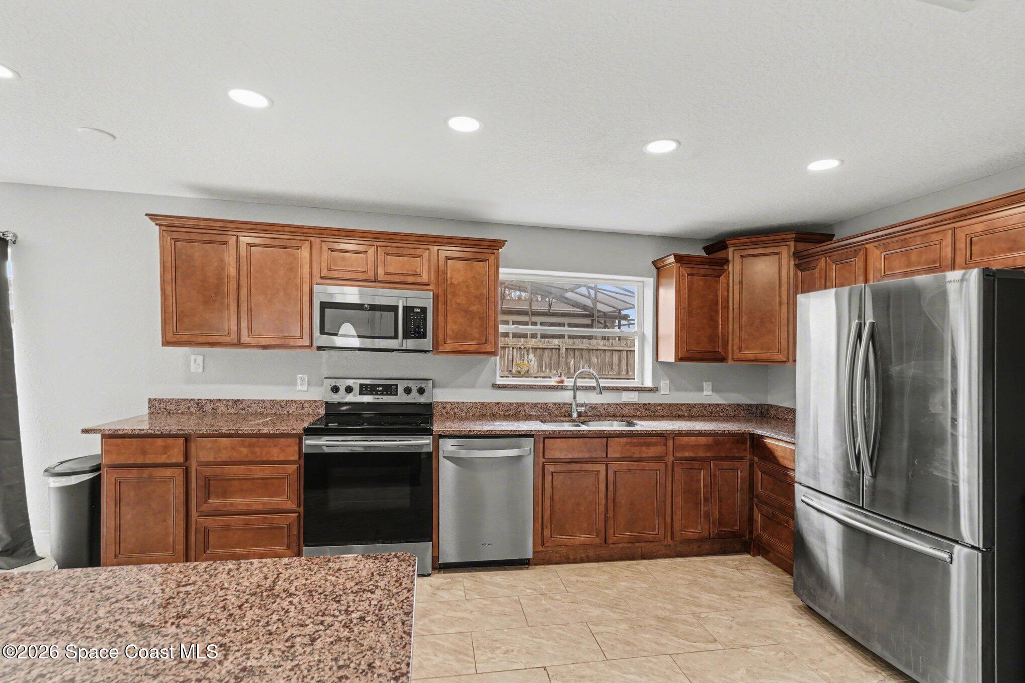 455 Riverside Avenue Merritt Island, FL 32953 - Photo 2 of 28 a kitchen with stainless steel appliances granite countertop a refrigerator a sink a stove a washer dryer and cabinets