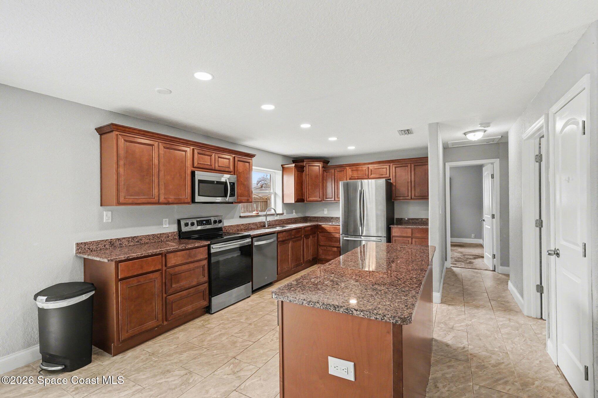 455 Riverside Avenue Merritt Island, FL 32953 - Photo 7 of 28 a kitchen with stainless steel appliances granite countertop a sink stove and refrigerator