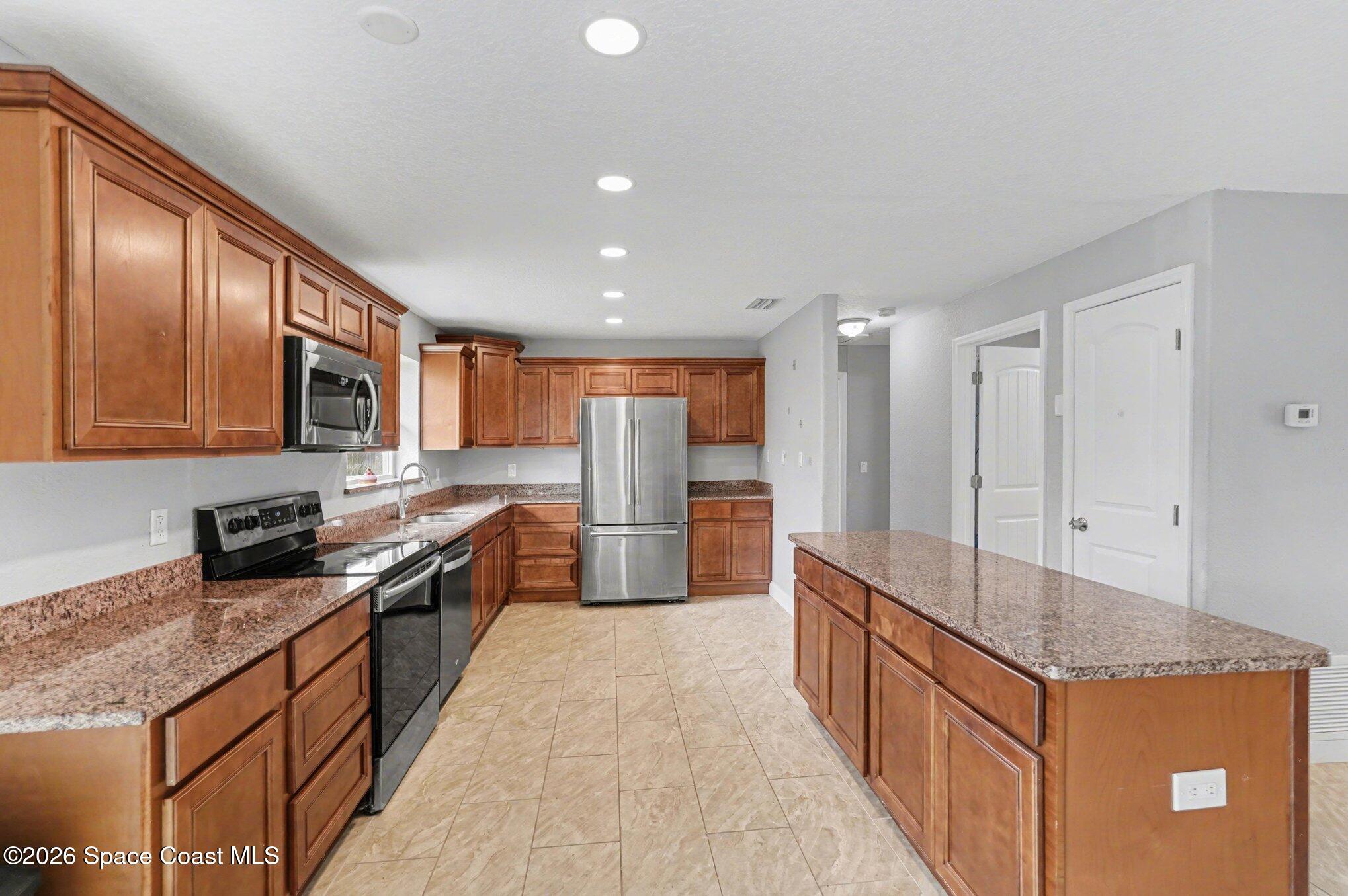 455 Riverside Avenue Merritt Island, FL 32953 - Photo 8 of 28 a large kitchen with stainless steel appliances granite countertop a stove a sink and a refrigerator