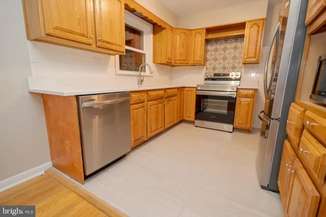a kitchen with stainless steel appliances granite countertop a stove a sink and a refrigerator with wooden cabinets