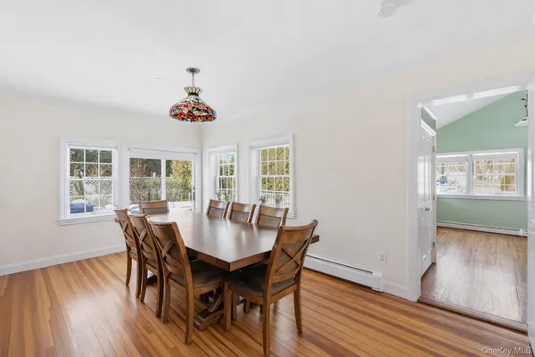 a dining room with wooden floor a chandelier a wooden table and chairs