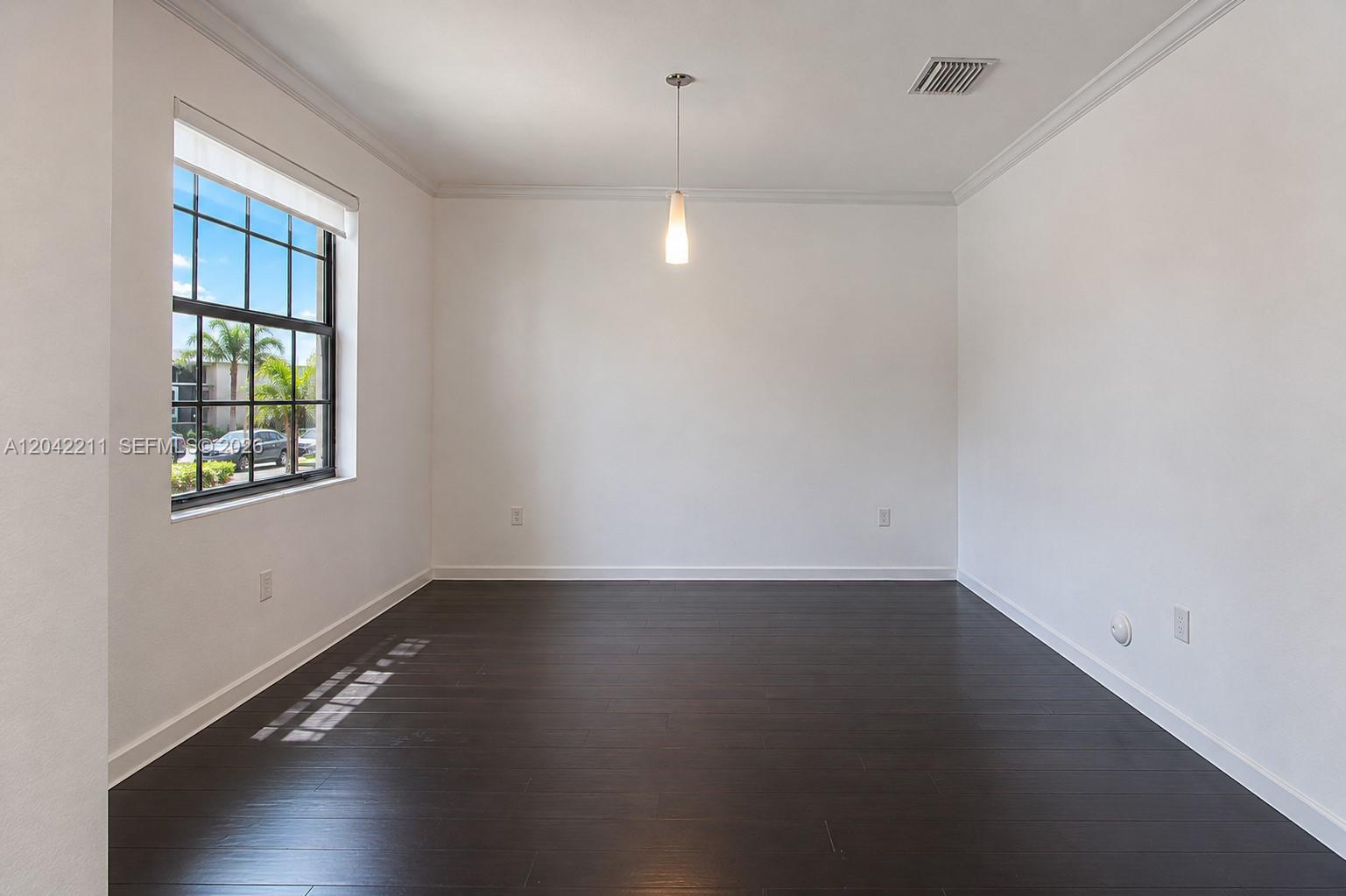 8954 West 35th Way Hialeah, FL 33018 - Photo 18 of 24 an empty room with wooden floor and windows