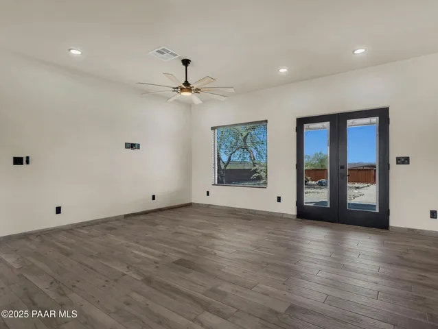 a view of empty room with wooden floor and fan