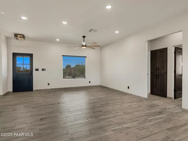 a view of an empty room with wooden floor and a kitchen