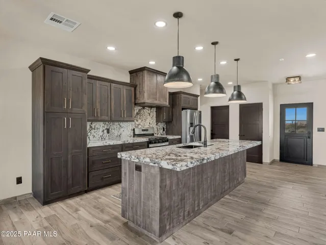 a large kitchen with kitchen island a counter space a sink and stainless steel appliances