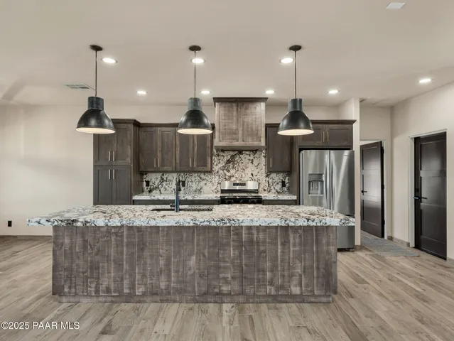 a kitchen with stainless steel appliances granite countertop a sink a stove and a refrigerator