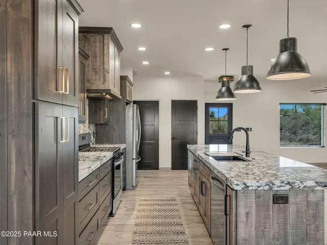 a kitchen with stainless steel appliances granite countertop a sink a stove and a refrigerator