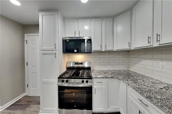 a kitchen with granite countertop white cabinets and stainless steel appliances