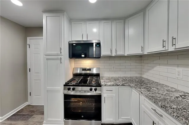 a kitchen with granite countertop white cabinets and stainless steel appliances