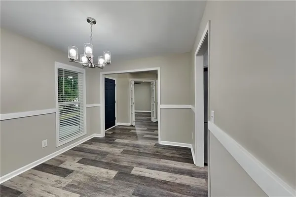 a view of a hallway with wooden floor and chandelier