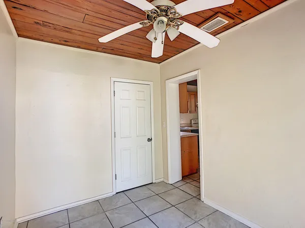 an empty room with chandelier fan and closet