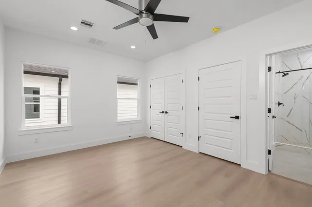 an empty room with windows and fan