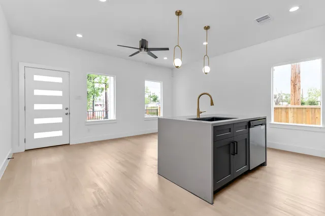 a kitchen with stainless steel appliances granite countertop a sink a stove a window and a hard wood floor